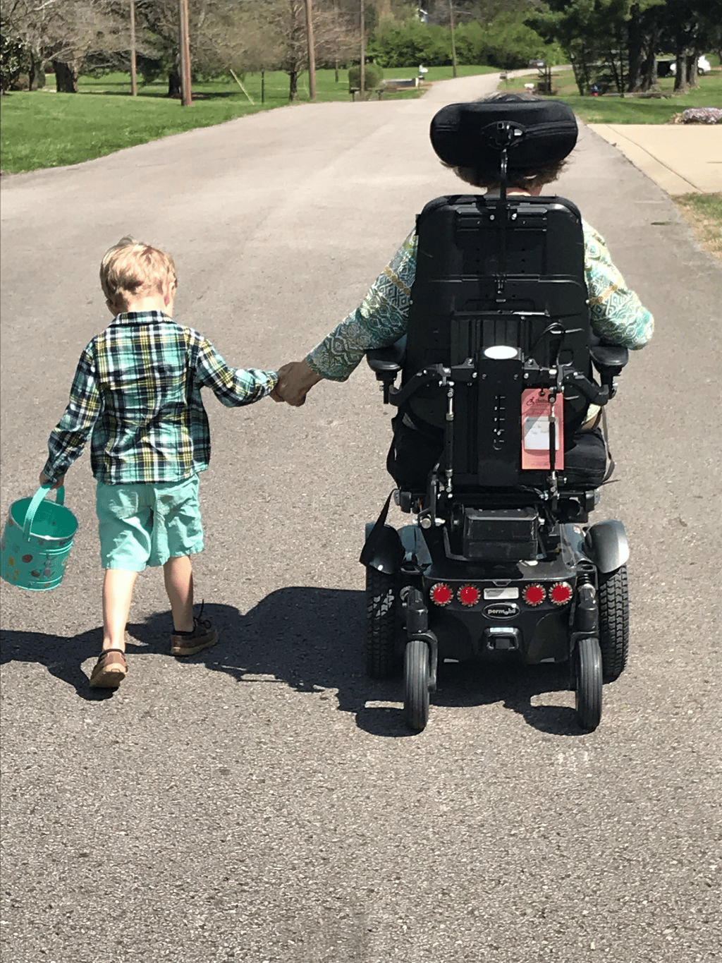 Patient in motorized wheelchair holding child's hand